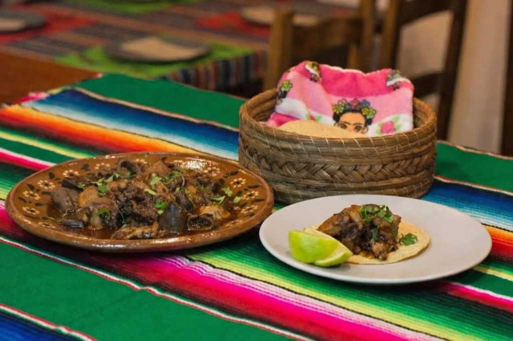 Platos tradicionales mexicanos servidos en vajilla de barro sobre mantel de sarape